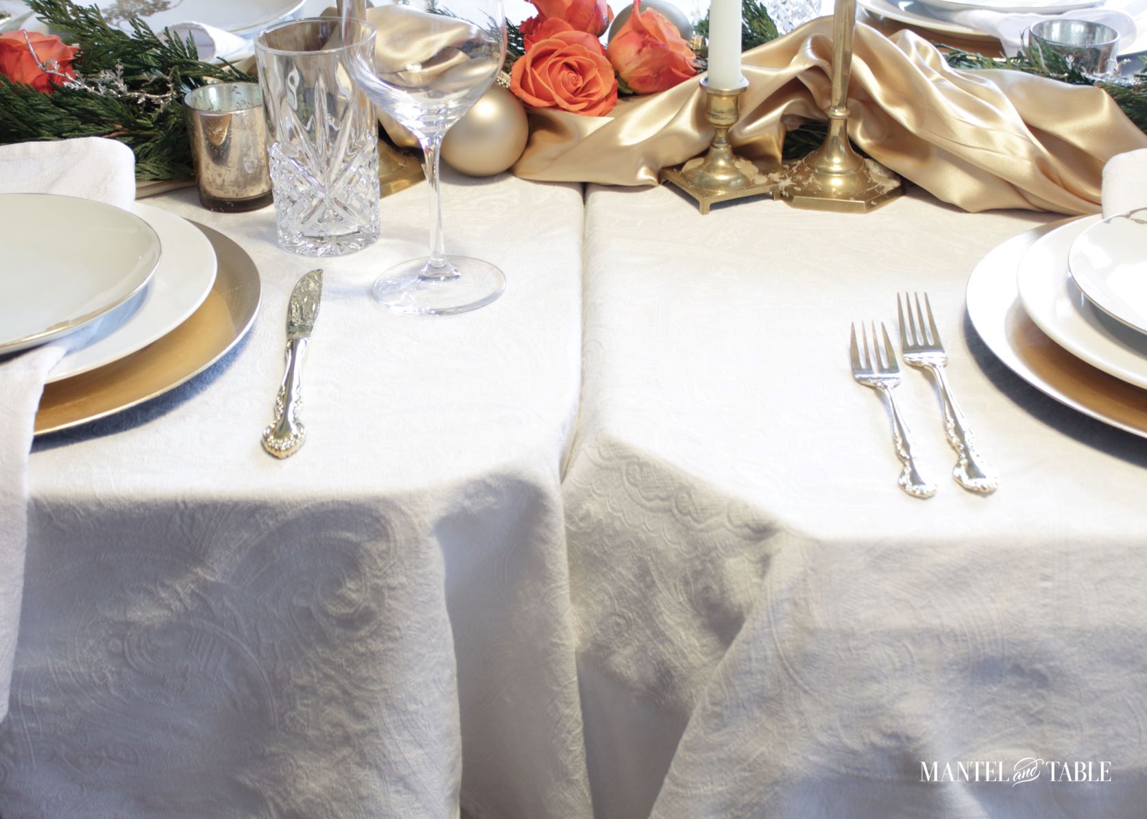 Two white tableclothed tables abutting each other, with gold satin centerpiece
