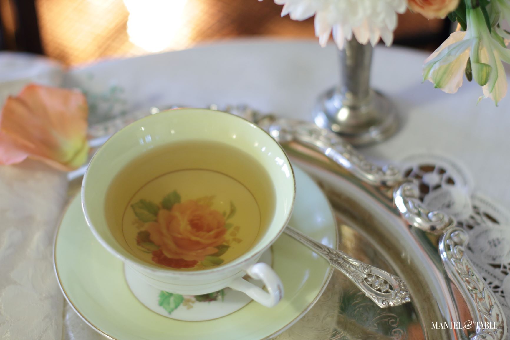 Yellow teacup with pink rose on the bottom. Filled with tea.