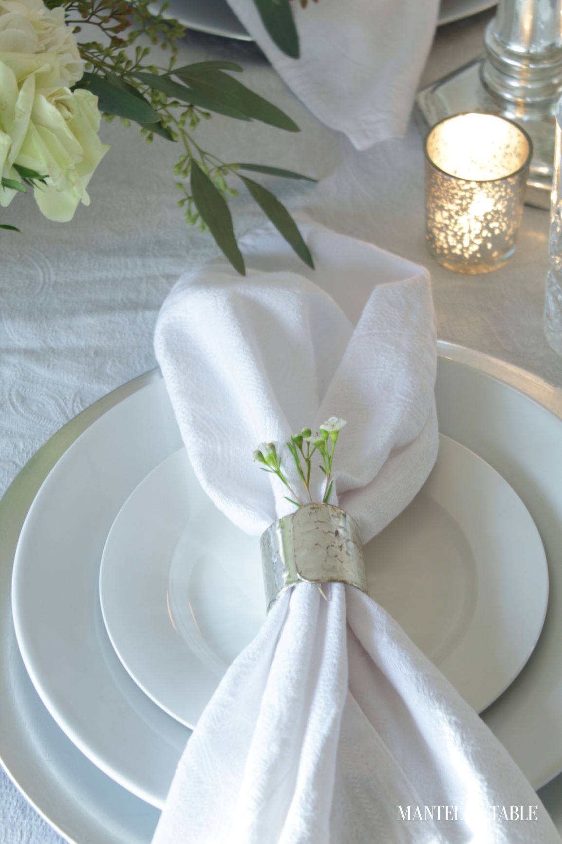 An Elegant St Patrick's Day Table ~ closeup of silver napkin ring with sprig of greenery with white flowers