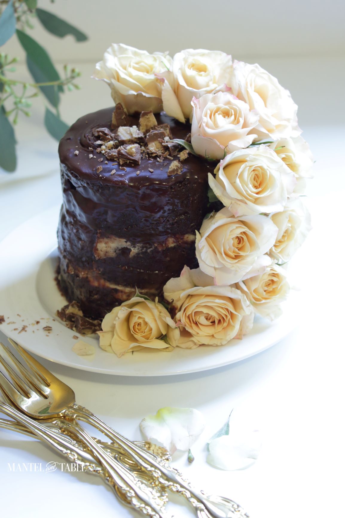 A tiny chocolate cake with gold forks and rose petals