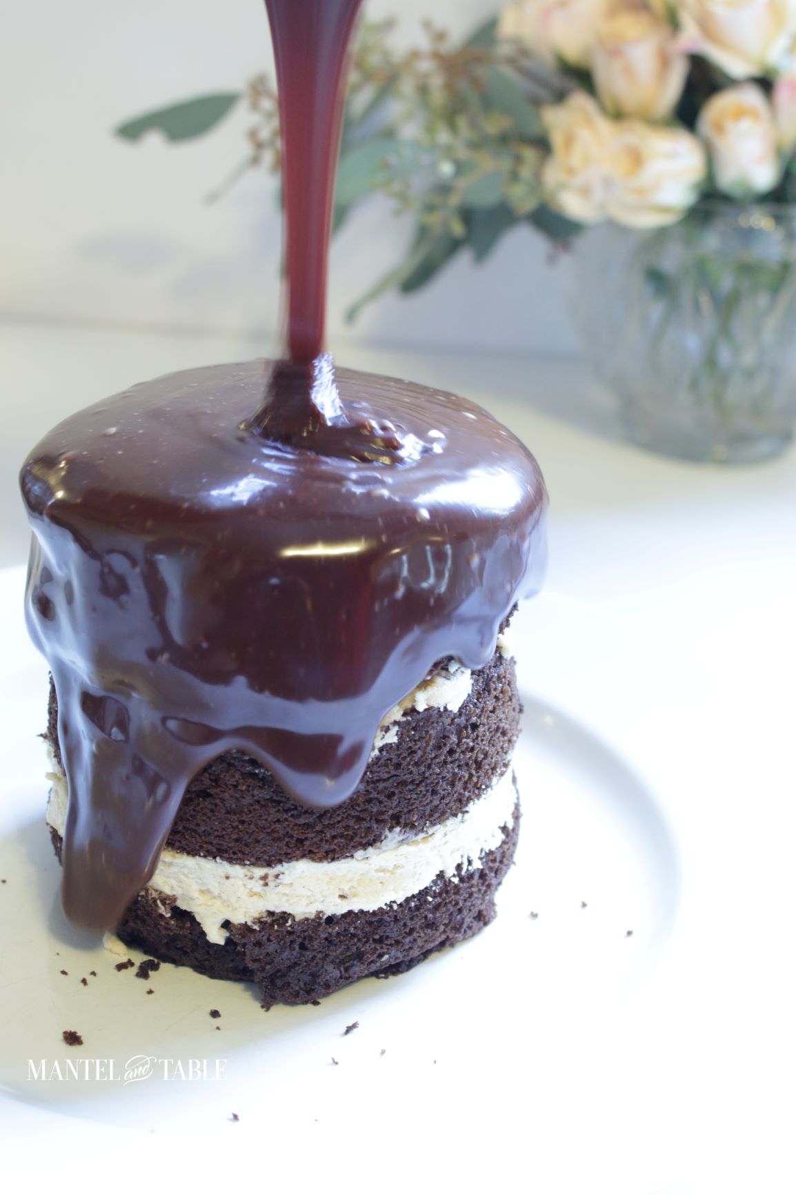 A tiny chocolate cake with ganache being poured over it