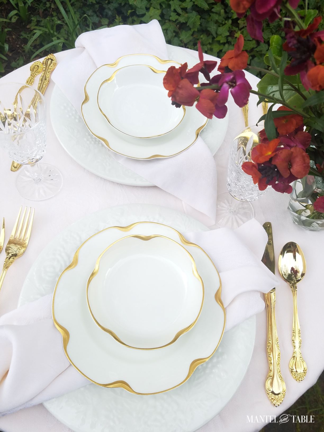 Two place settings of white and gold china with pink linens