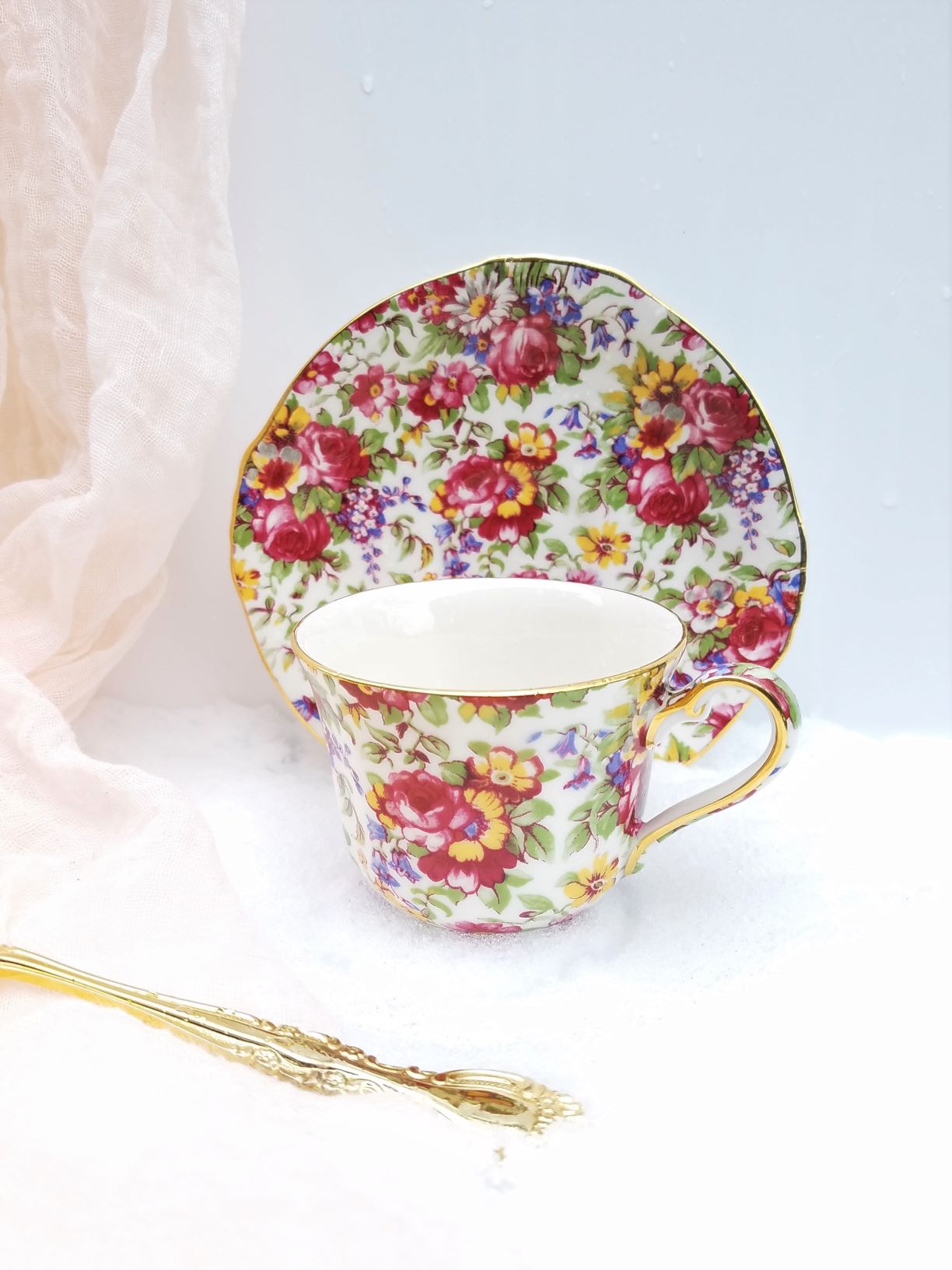 Maroon yellow & blue teacup and saucer in the snow