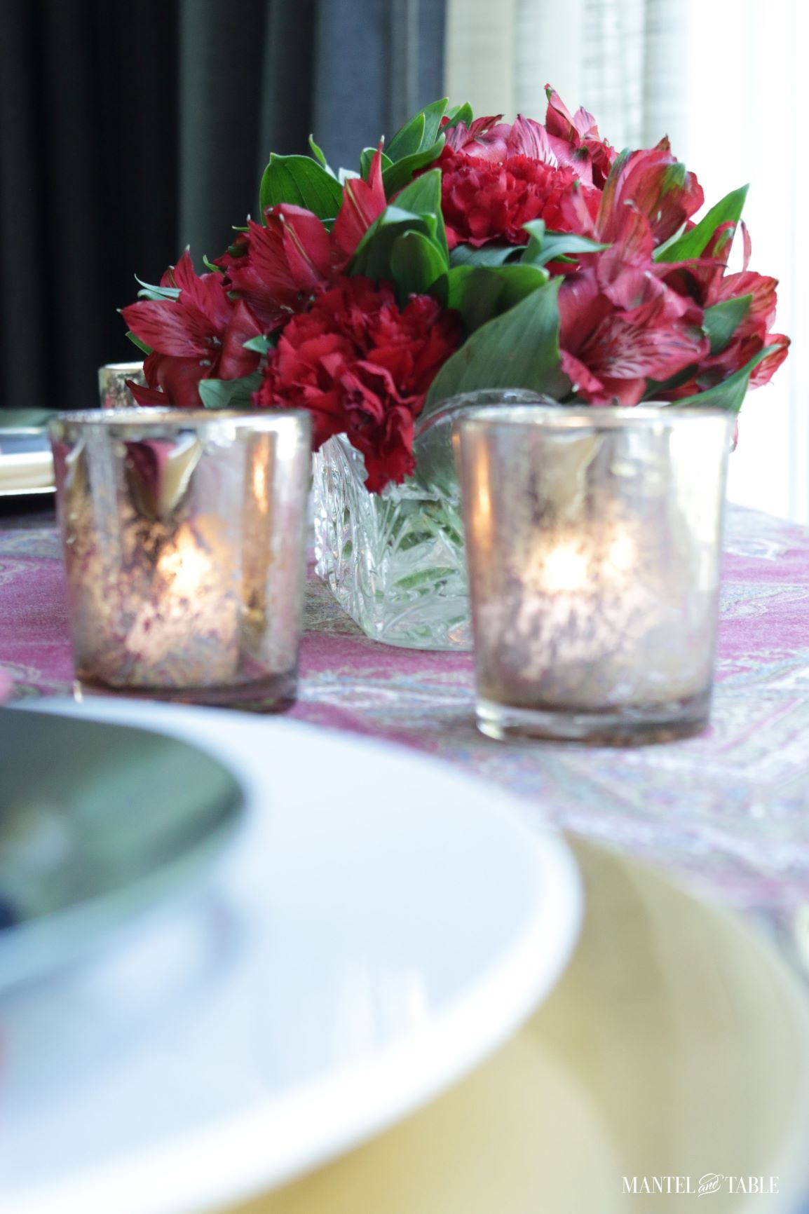 Cozy tablescape ~ closeup of gold votive candle holders & red flowers