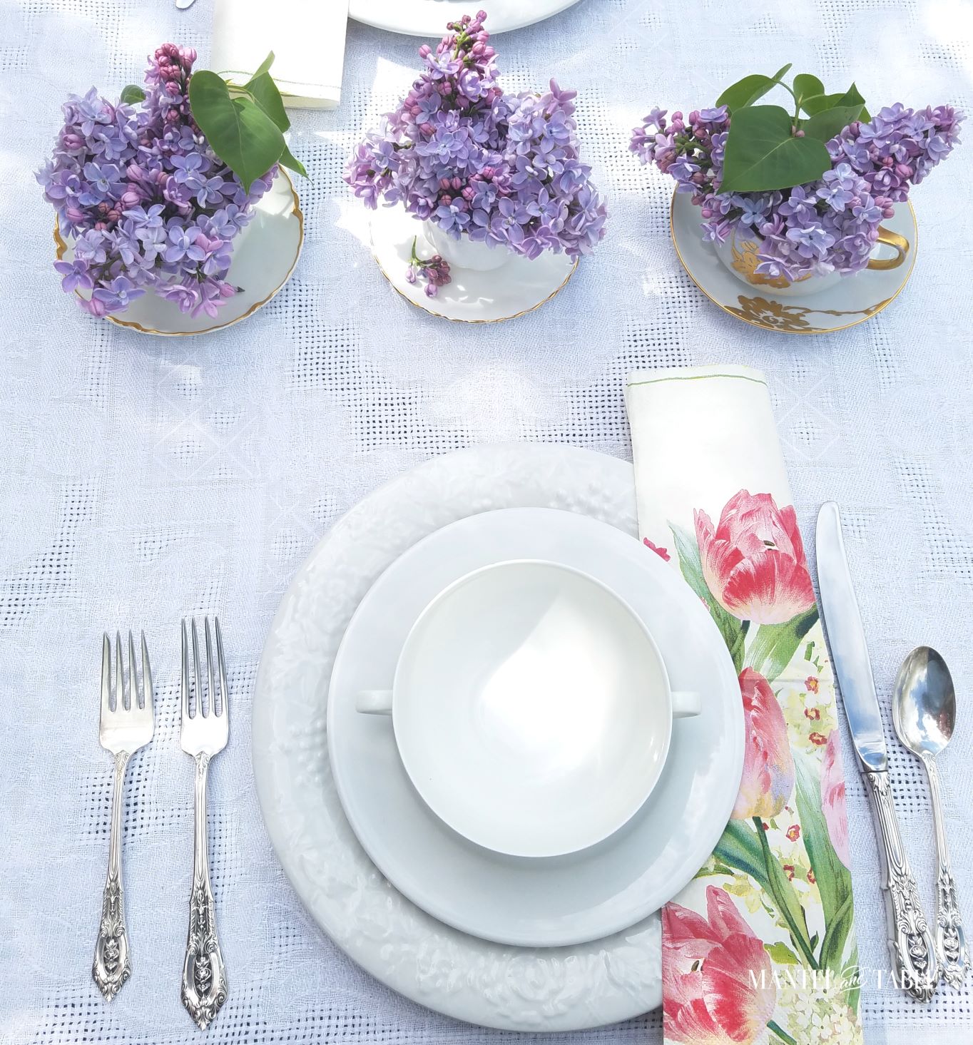 Three white and gold teacups holding lilacs for a centerpiece
