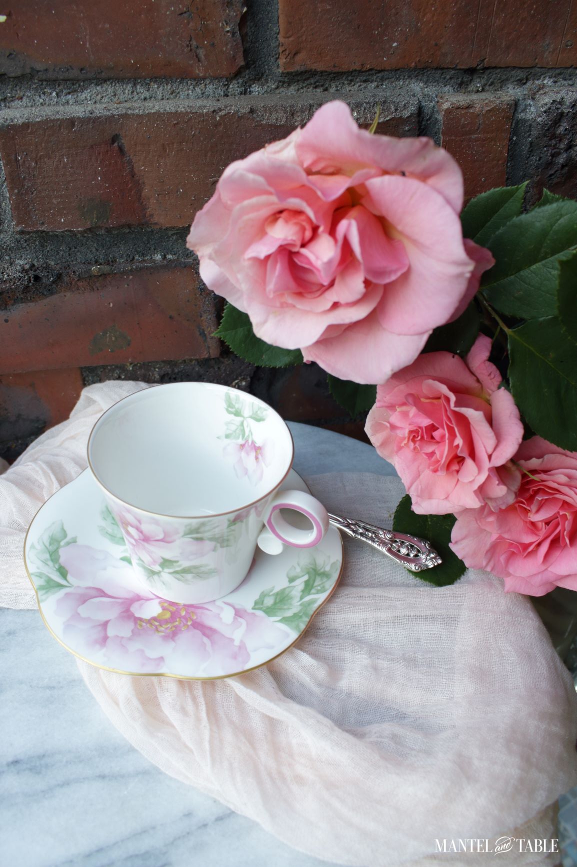Our Traveling Teacup - pink and white floral cup and saucer on marble table with pink roses