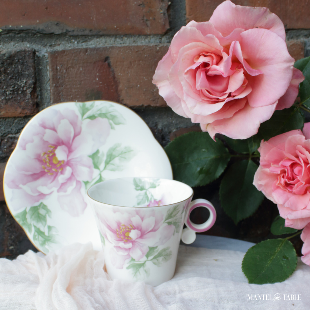 The Traveling Teacup on marble against red brick, with pink roses