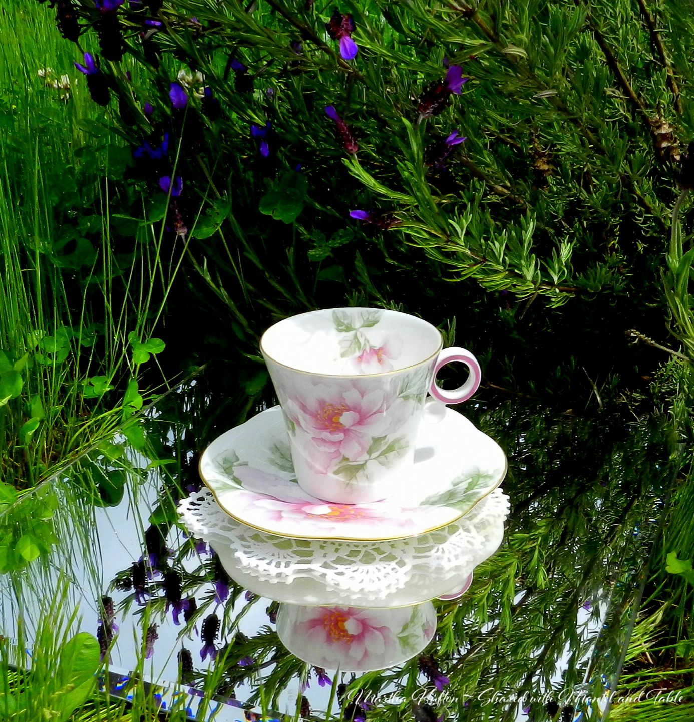 Teacup and saucer on a mirror in a grassy wildflower garden