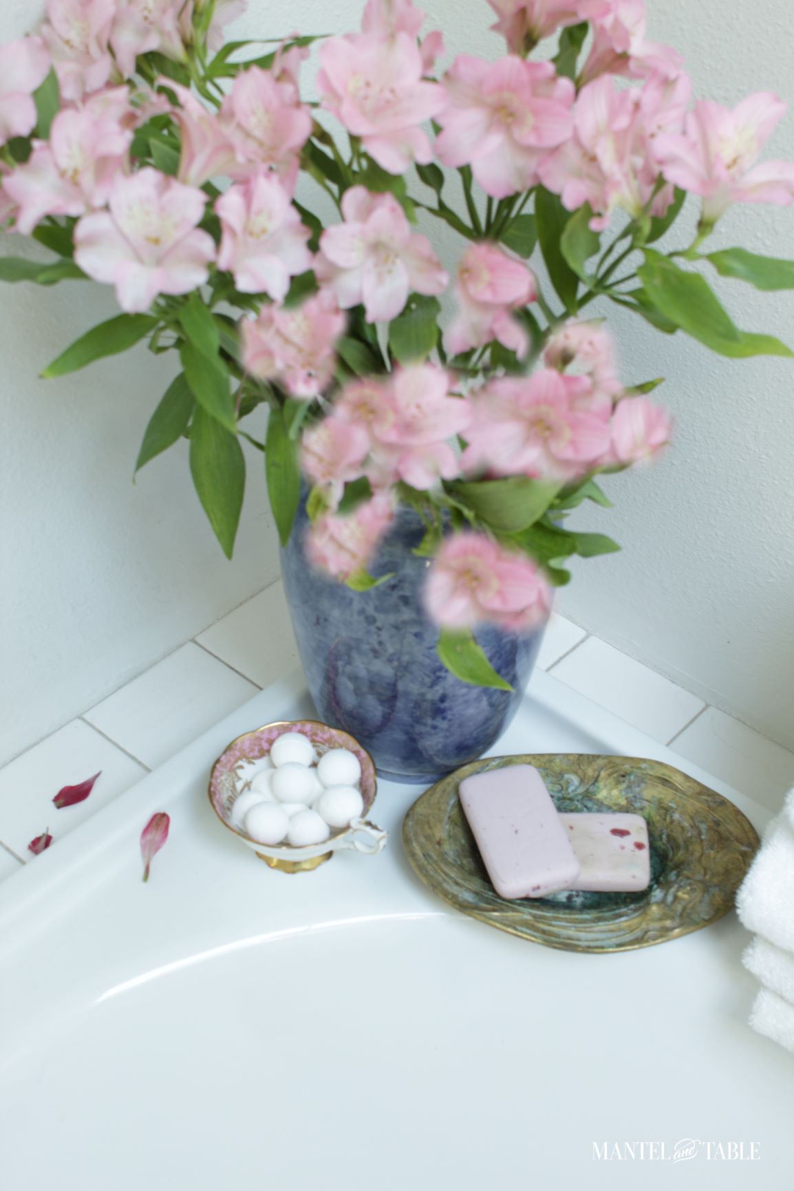 Teacup holding small white bath balls on corner of bathtub