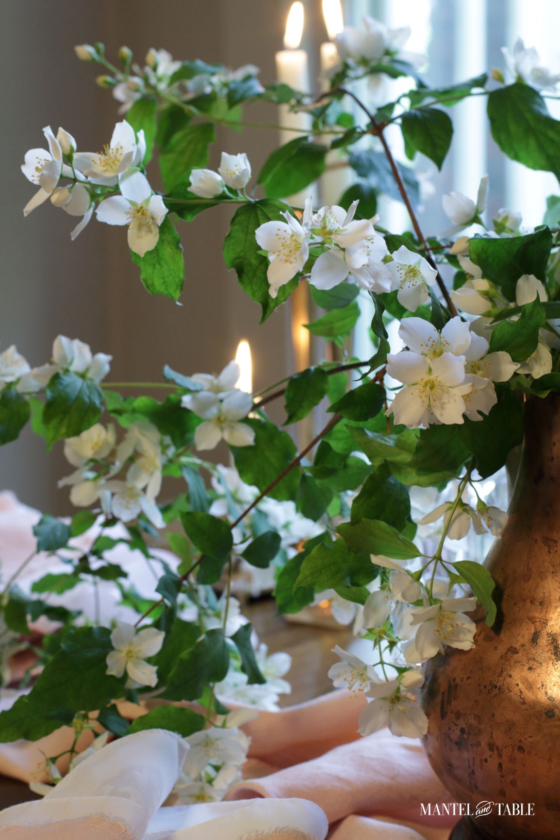 Copper pitcher and white blossom centerpiece with Blush table linens