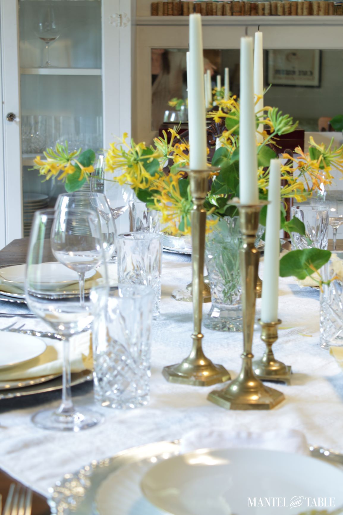 Several tall brass candlesticks on set table