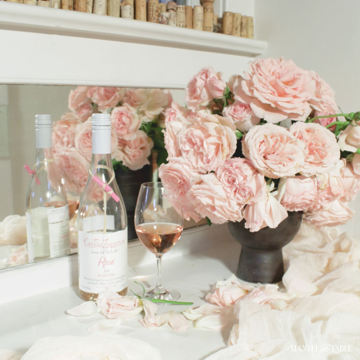Rosé wine in a wine glass, bottle, and pink roses