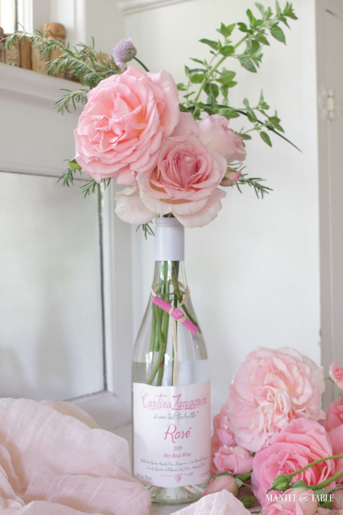 arrangement of pink roses and herbs in a wine bottle