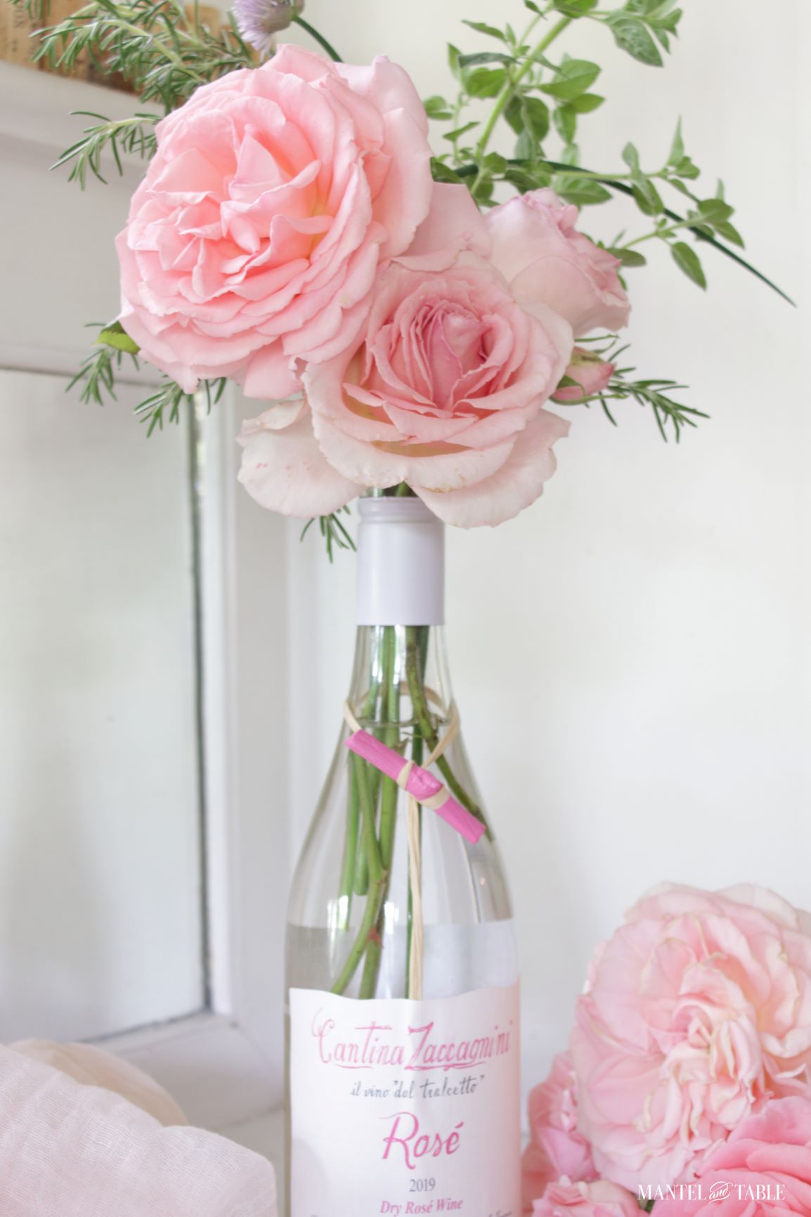 Pink roses and herbs in a wine bottle