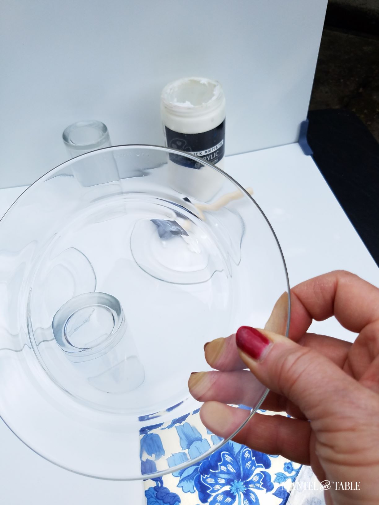 A hand holding a clear glass salad plate