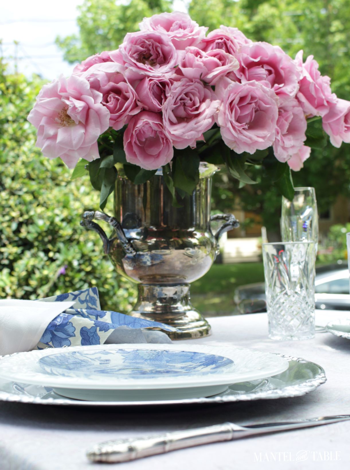 Large centerpiece of pink roses on blue & white tablescape