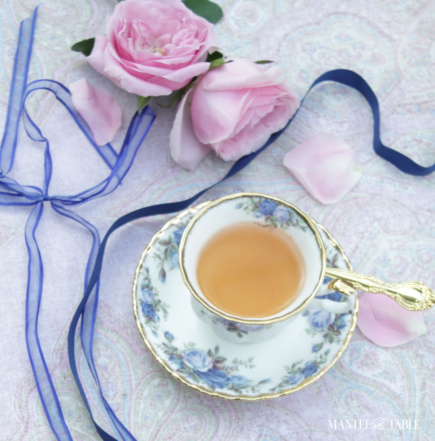 Blue flowered teacup flat lay with pink roses and blue ribbon