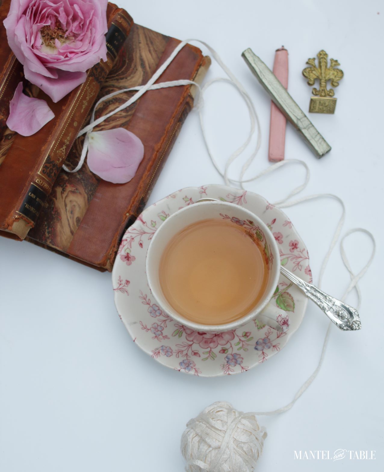 teacup flat lay with books, roses, yarn, and sealing wax