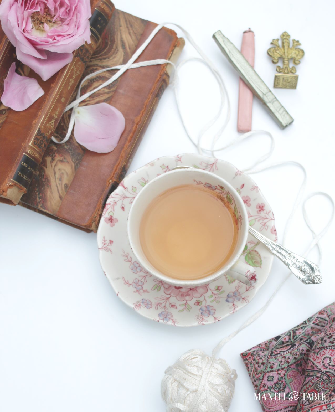 Teacup small leather bound books, sealing wax & stamp, rose petals view from above