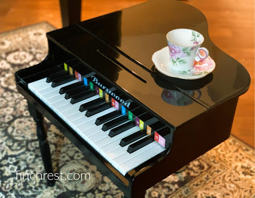 Floral teacup & saucer on a toy grand piano
