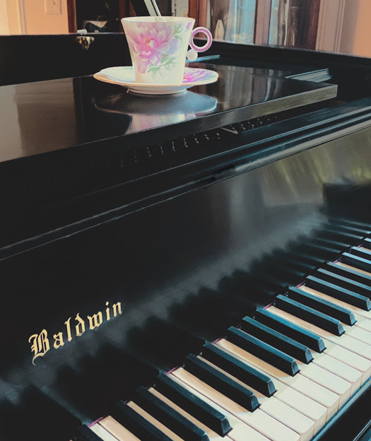 Teacup travels - floral teacup on a glossy black grand piano