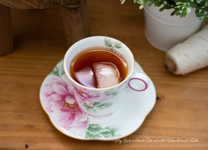 Pink flowered teacup with ice cube in tea