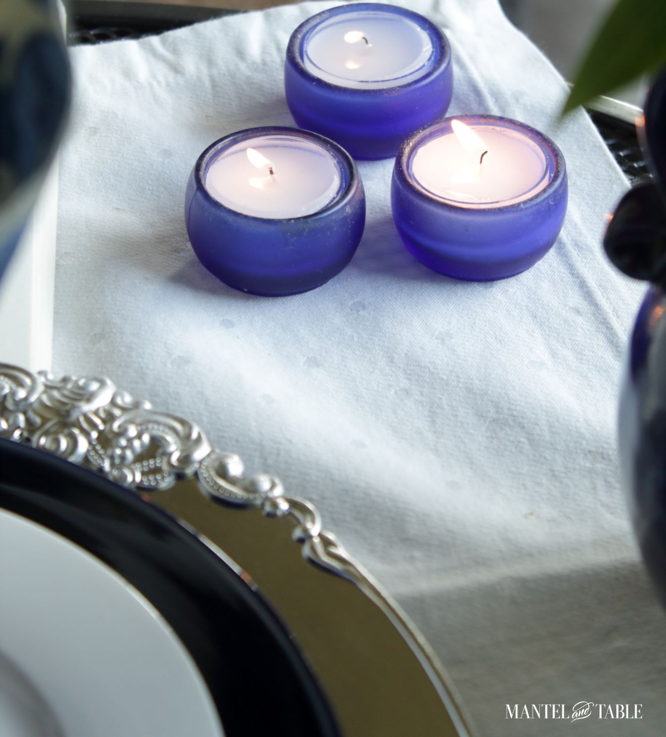 Closeup of cobalt blue votive candle holders in blue and white tablescape
