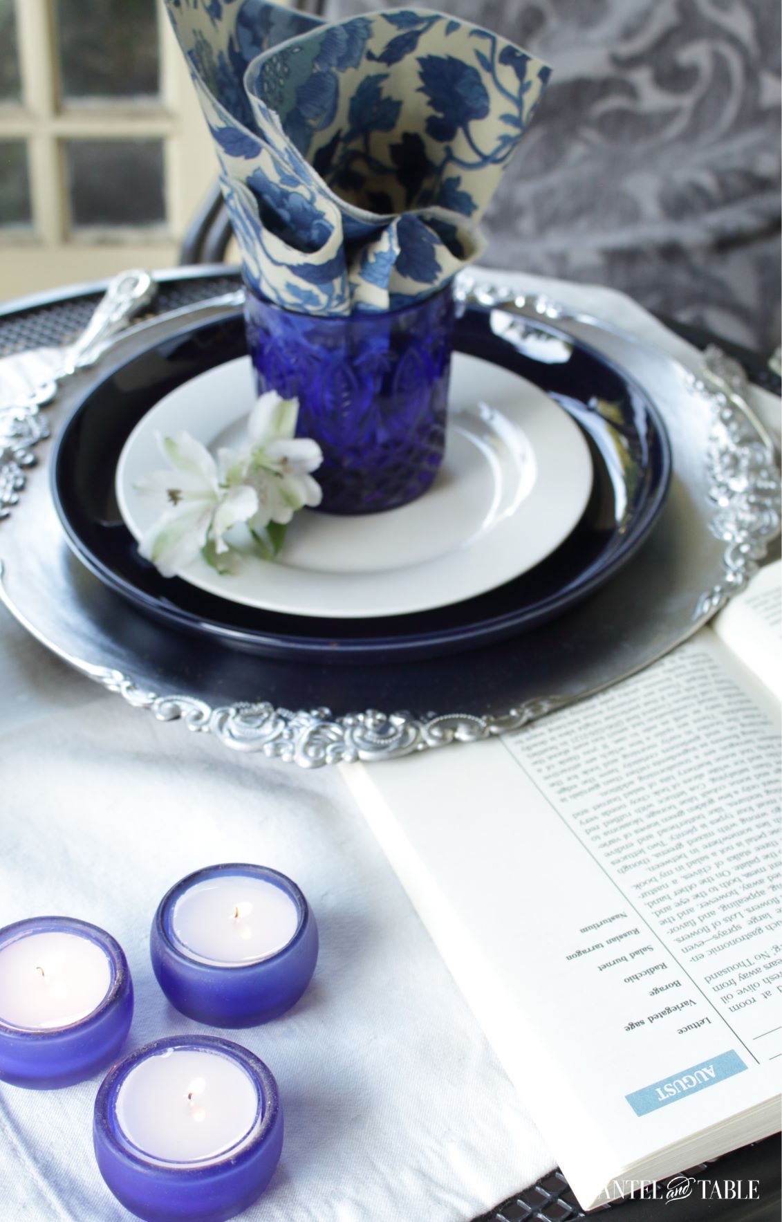 Book, candles, and plate stack in a blue and white tablescape