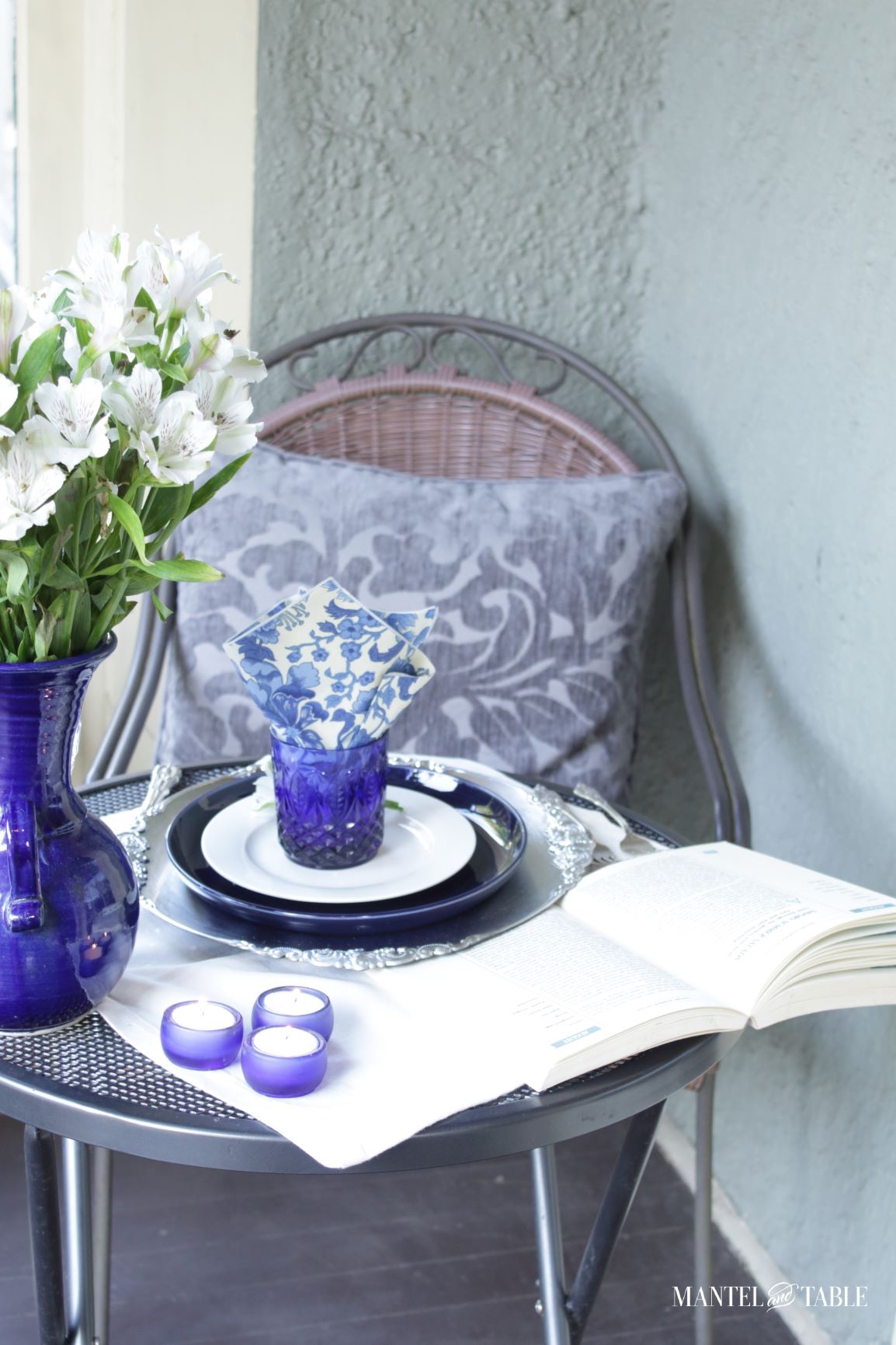 Blue and white tablescape. Close up of table with big blue pillow on the chair