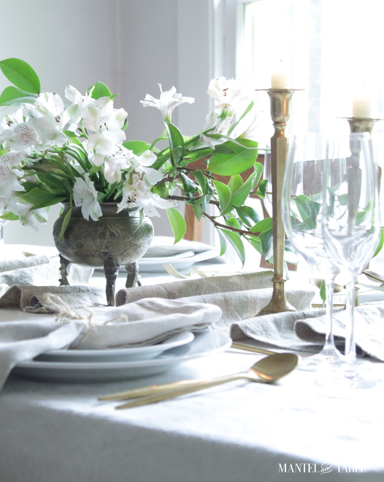 Side view of flower arrangement on table runner, with lighted candles