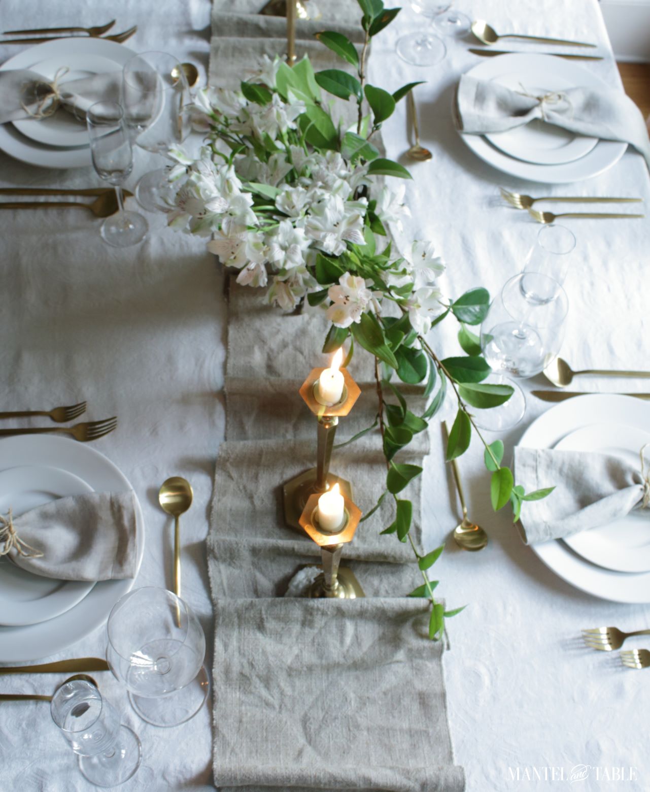 Natural colored linen table runner down the center of a white & gold tablescape
