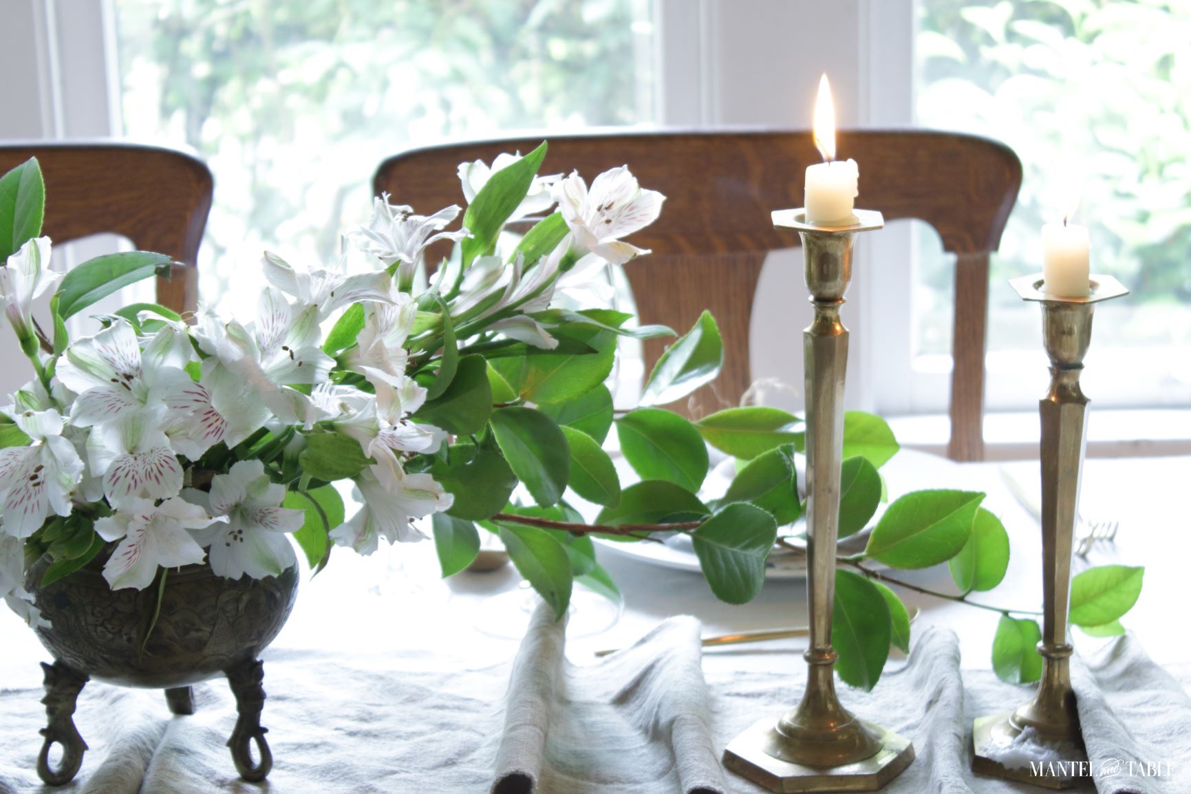 Closeup of flower arrangement and candles on table runner