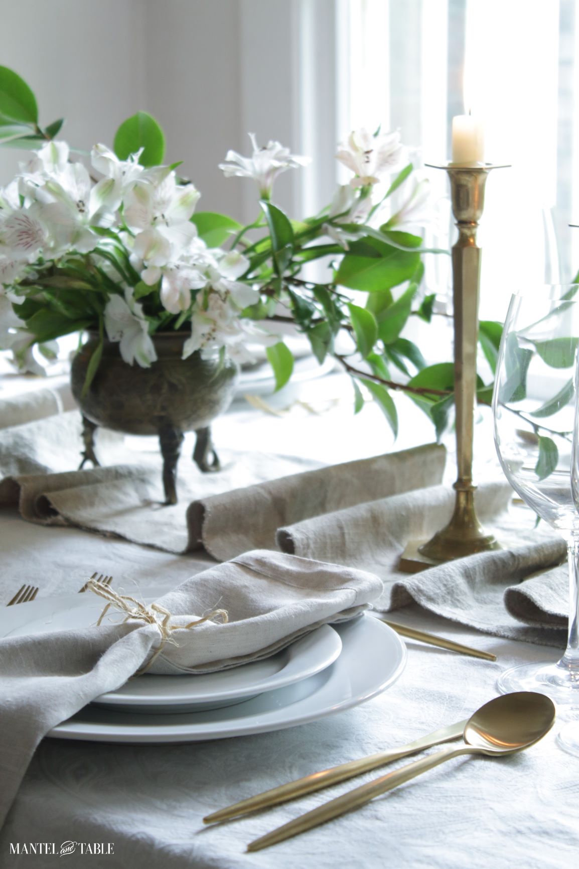 Table runner on white and gold table. white flowers in brass pot