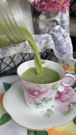 Pink & white teacup almost full of matcha being poured in. Ready for a matcha tea party