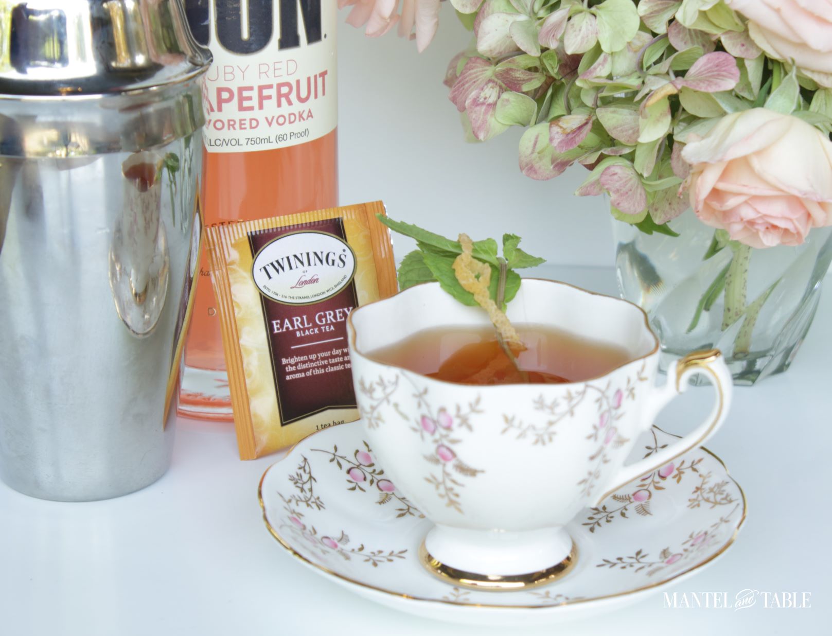 Cocktail in a teacup with pink flowers, silver shaker