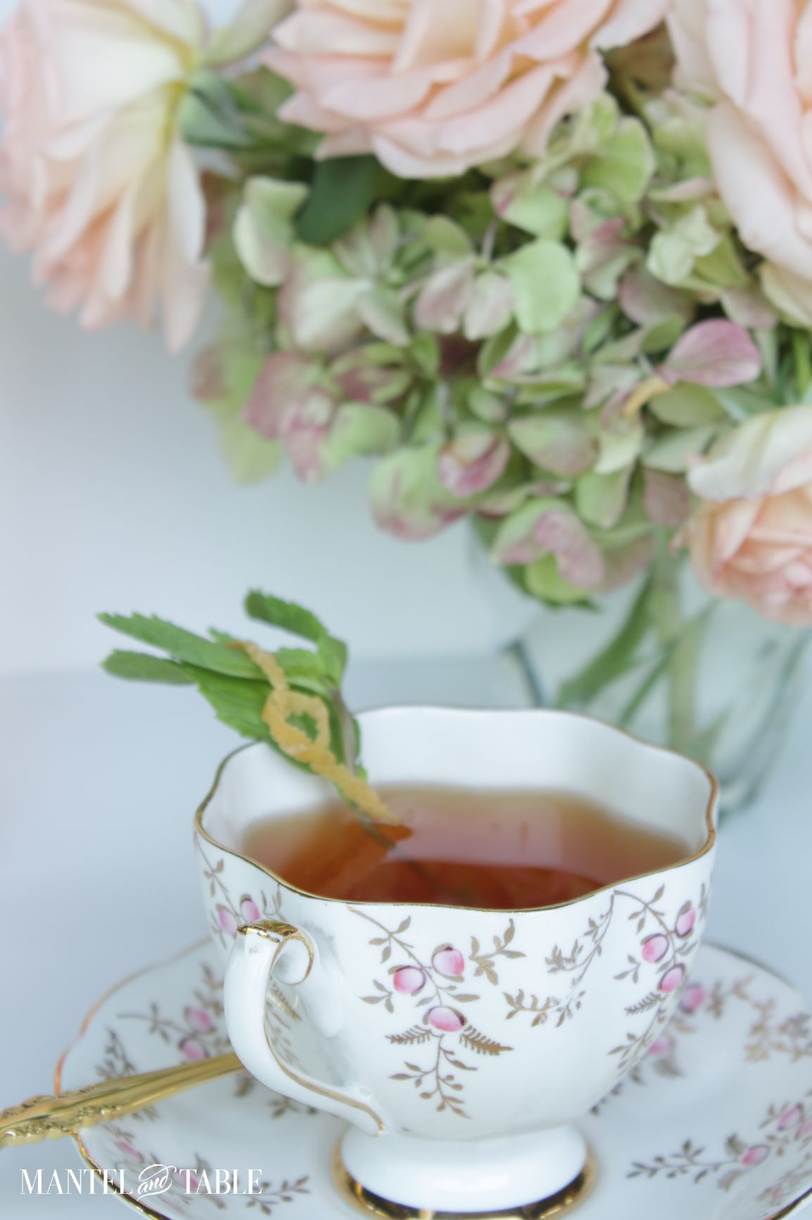 Cocktail in a teacup with green hydrangea and pink roses