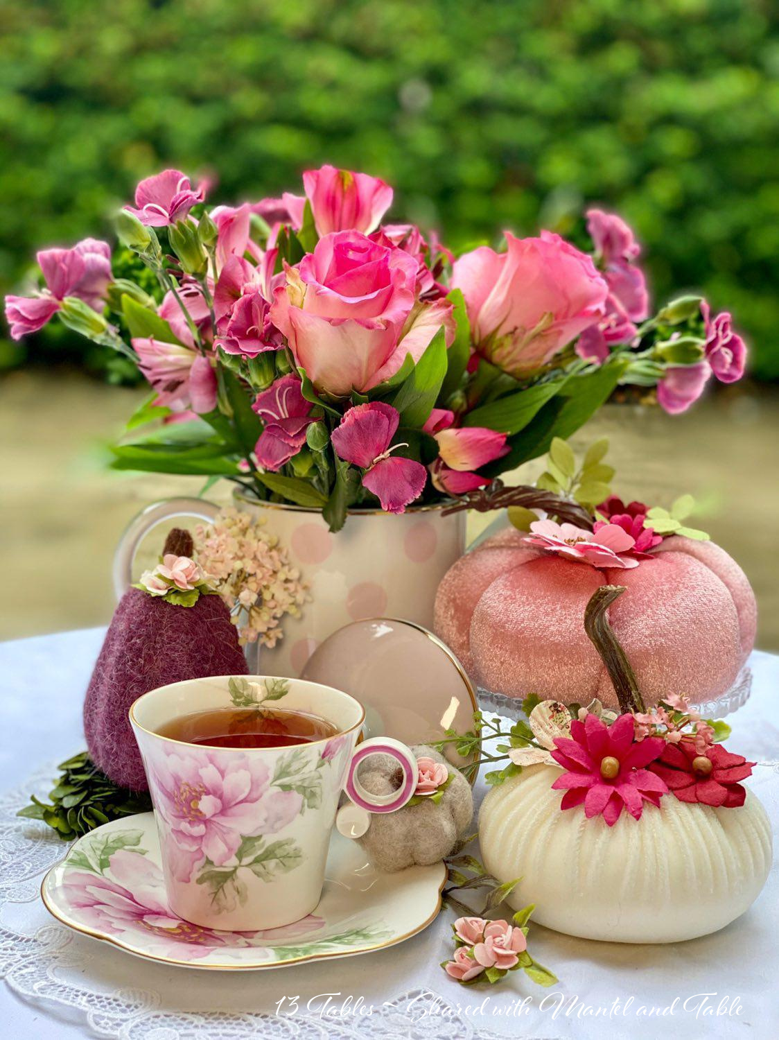 View of full table with teacup, pink pumpkin and flowers
