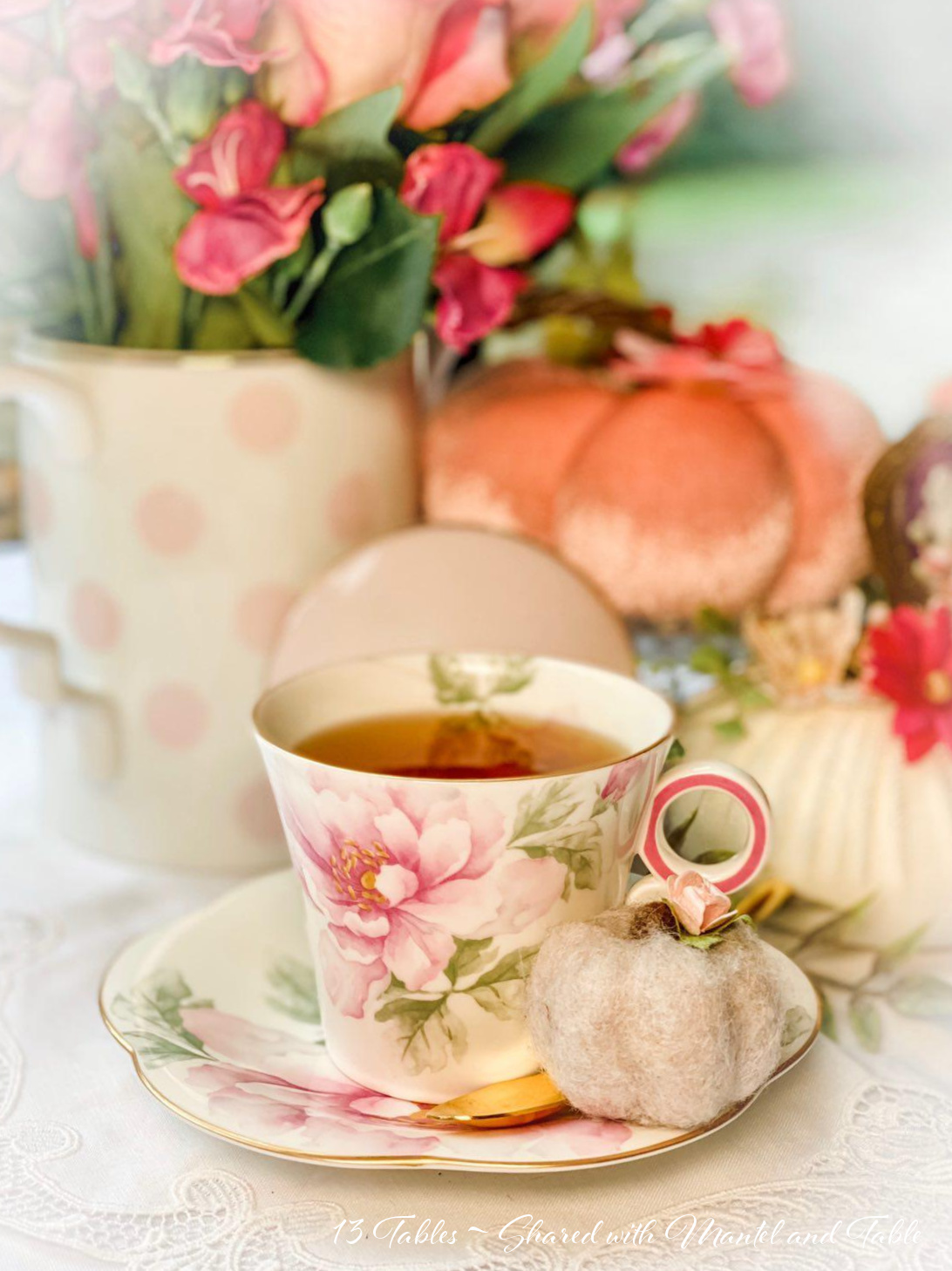 Closeup of pink flowered teacup on white lace tablecloth