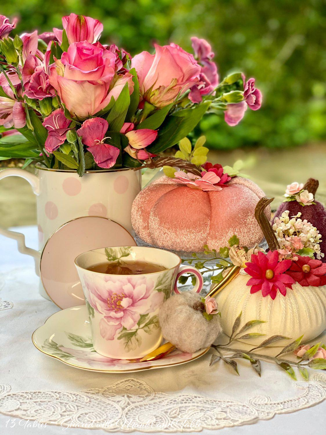 Decorated fabric pumpkins on a table with flowers, teacup