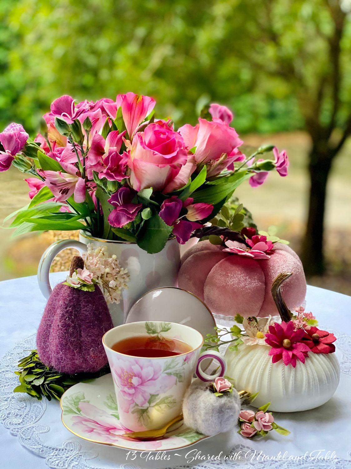 Pink flowered teacup with decorated pink pumpkin, also purple and white ones.