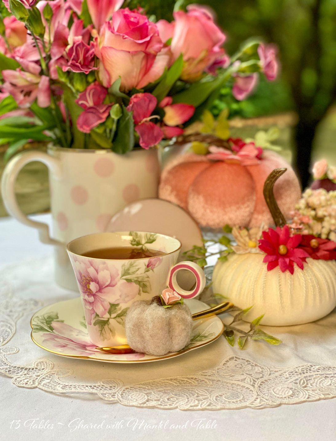 Pink flowered teacup on table with velvet pink pumpkin, pink flowers