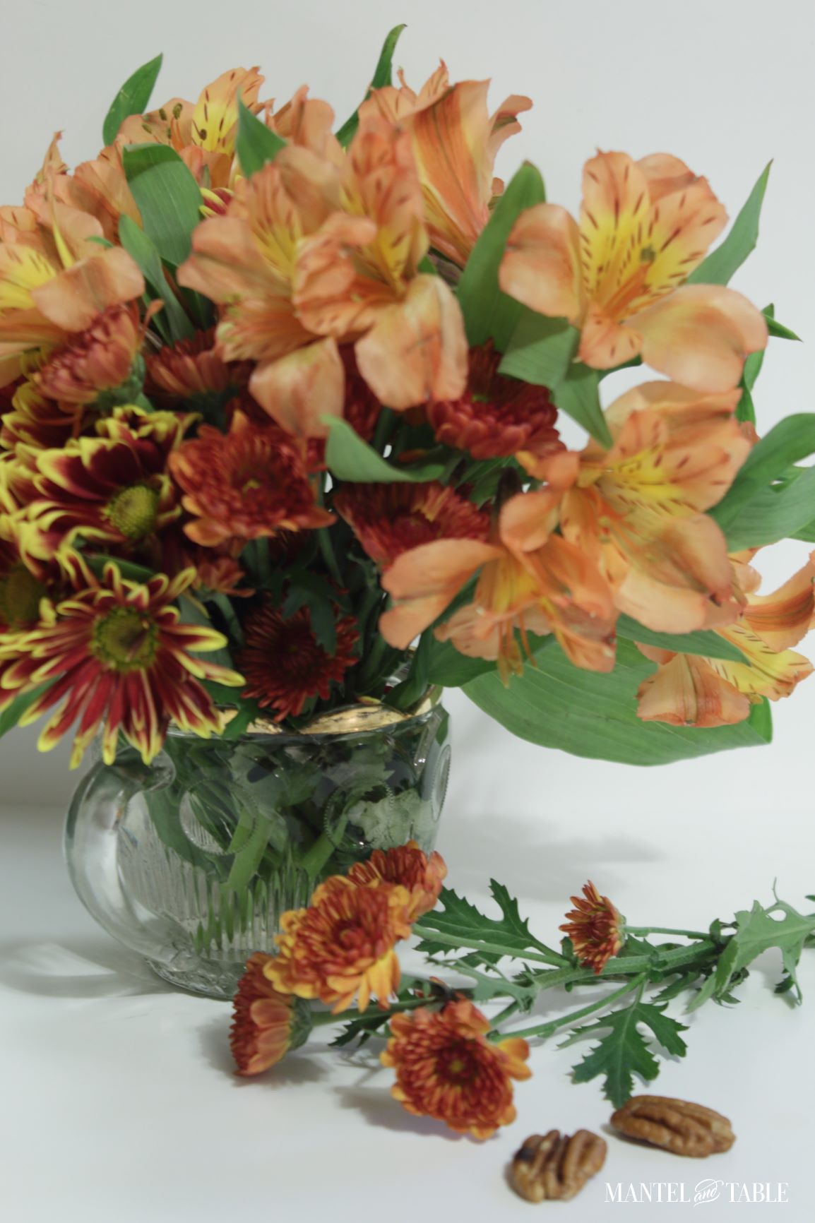 Closeup of orange and rust colored flowers in a gold rimmed, clear glass vase