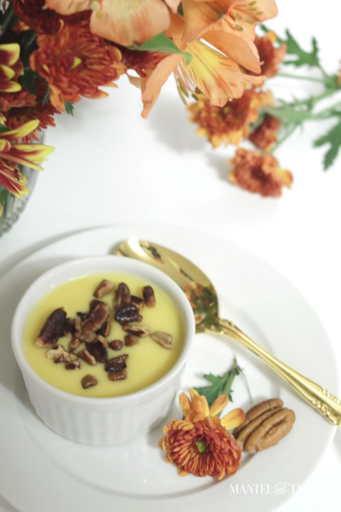 Pumpkin pot de creme with nuts on plate with gold teaspoon, rust flower and pecan half