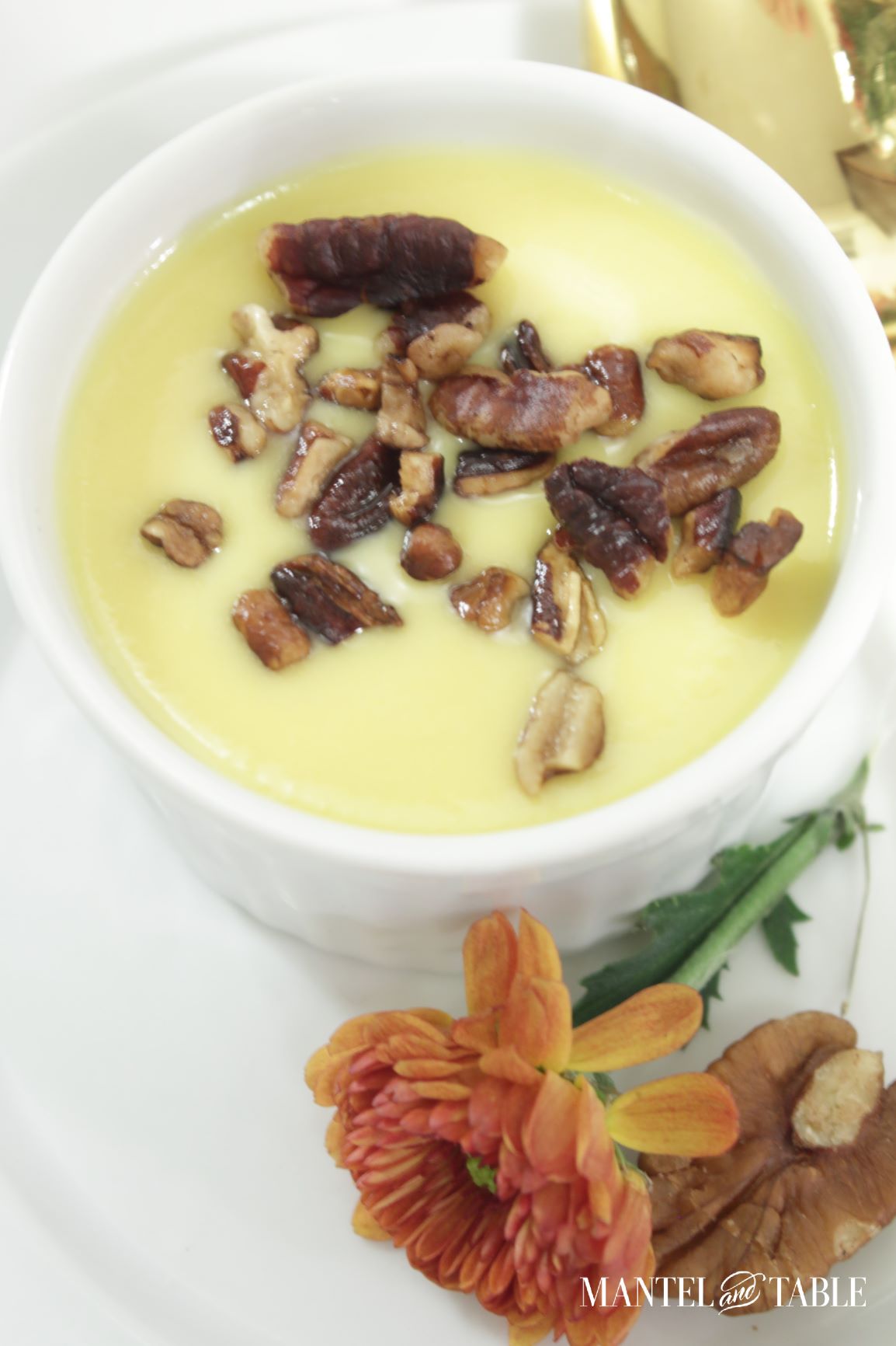 Pumpkin pot de creme with toasted pecans ~ closeup with rust colored flower on plate