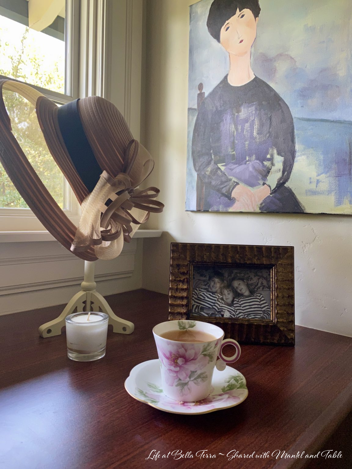 Teacup with tea on cabinet, family photo, hat on a stand