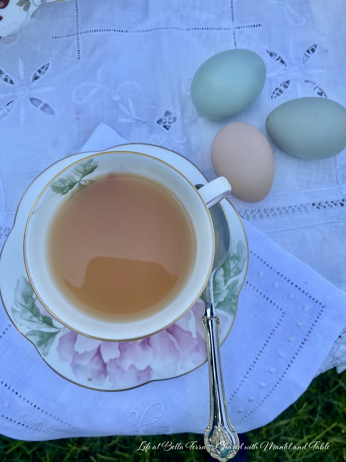 Overhead view of tea in teacup with fresh blue and tan eggs