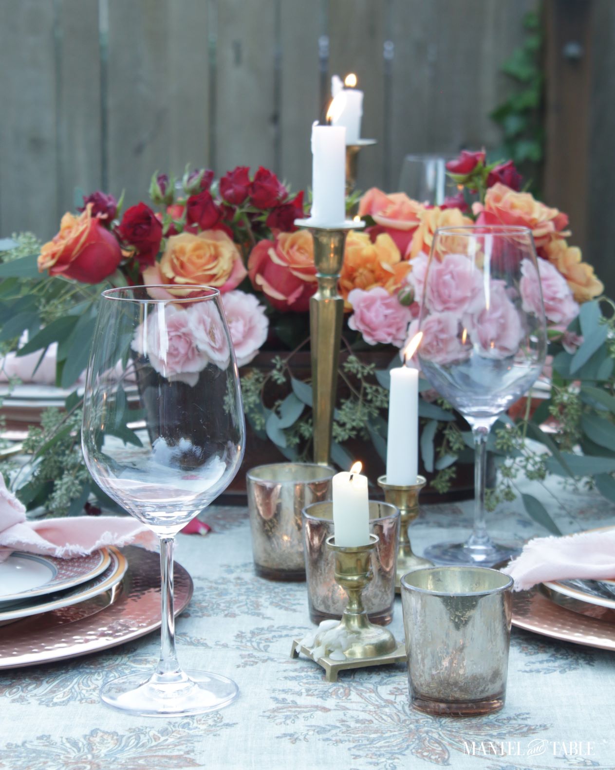 Closeup of wine glasses and candles in a pink and orange tablescape
