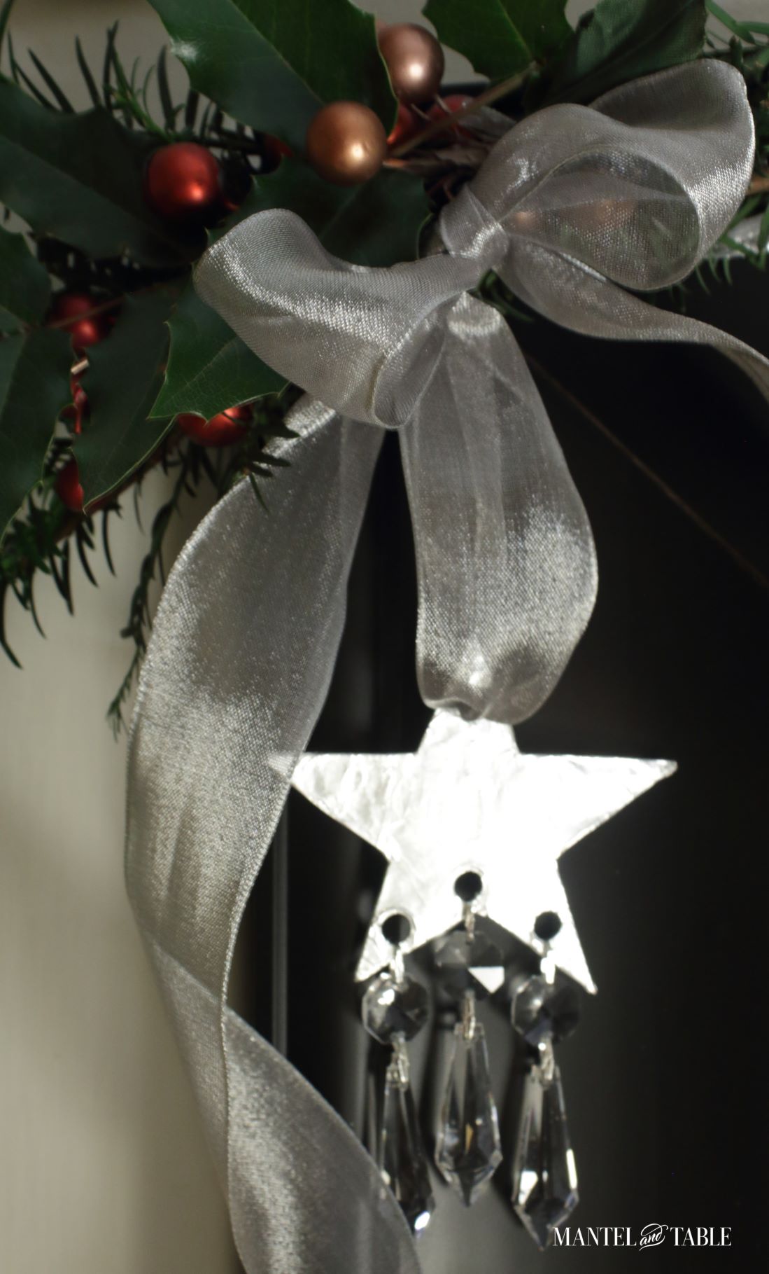 Elegant DIY Christmas Ornament hanging on holiday greens with sheer silver ribbon against a black frame