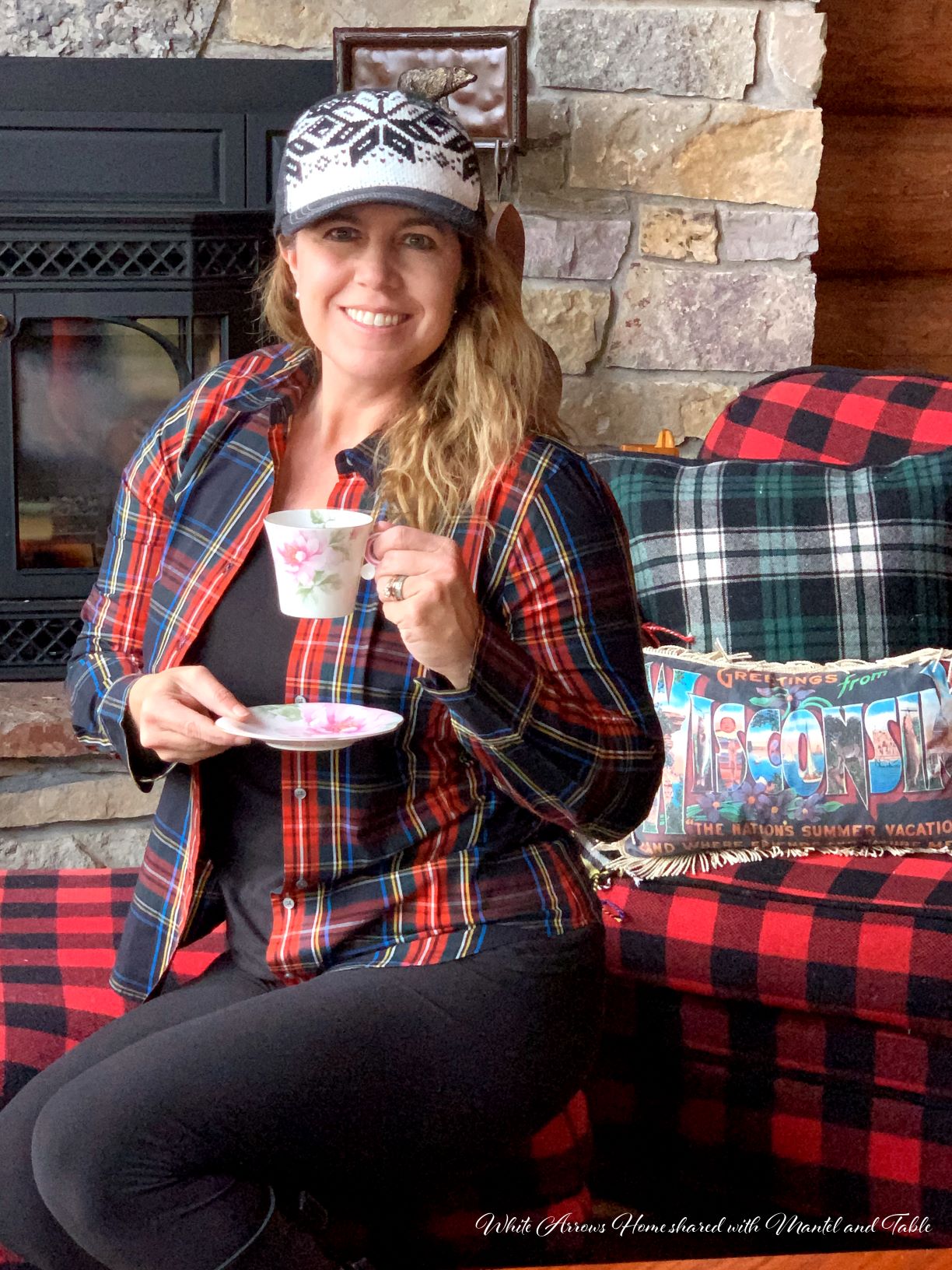 Lovely Kristin by the fireplace wearing a plaid shirt and holding the Traveling Teacup