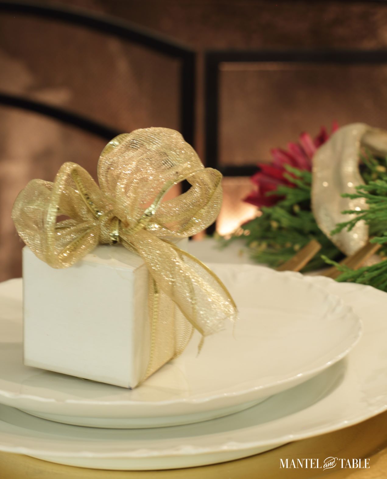 Closeup of white box with gold ribbon on white plates